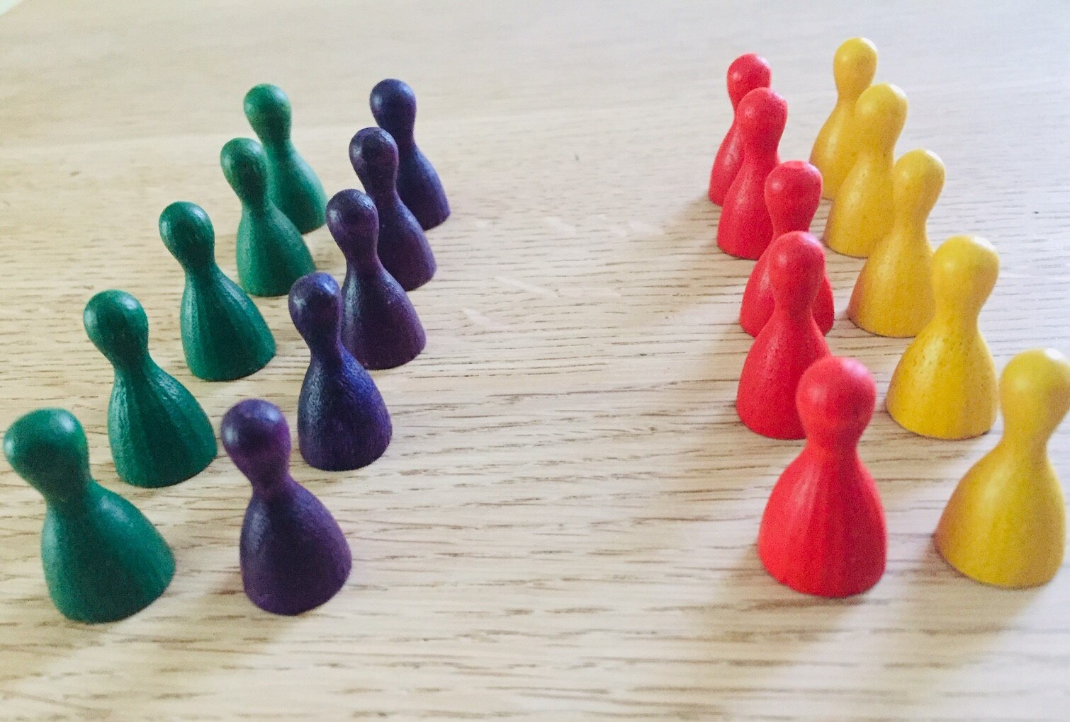 Brettspielfiguren verschiedener Farben stehen sich in zwei Doppelreihen gegenüber.