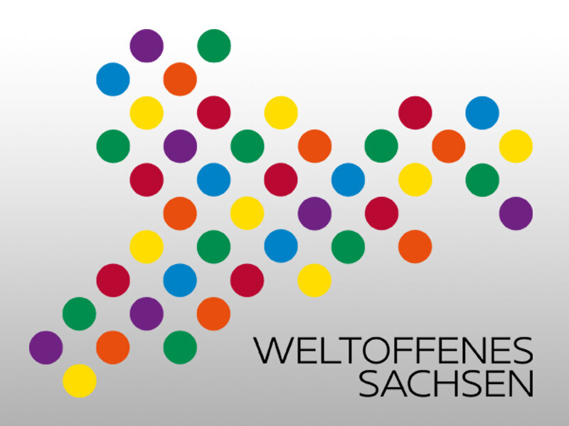 Viele verschiedenfarbige, gleichgroße Kreise sind auf weißem Hintergrund zu einem abstrakten Muster angeordnet. Darunter steht der Schriftzug „Weltoffenes Sachsen“ – das Bild vermittelt Offenheit, Vielfalt und Vernetzung.
